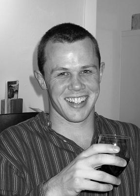 Greyscale image of Jon Peirce in roughly 2002. Jon is looking much younger than now, with short dark hair and clean shaven.